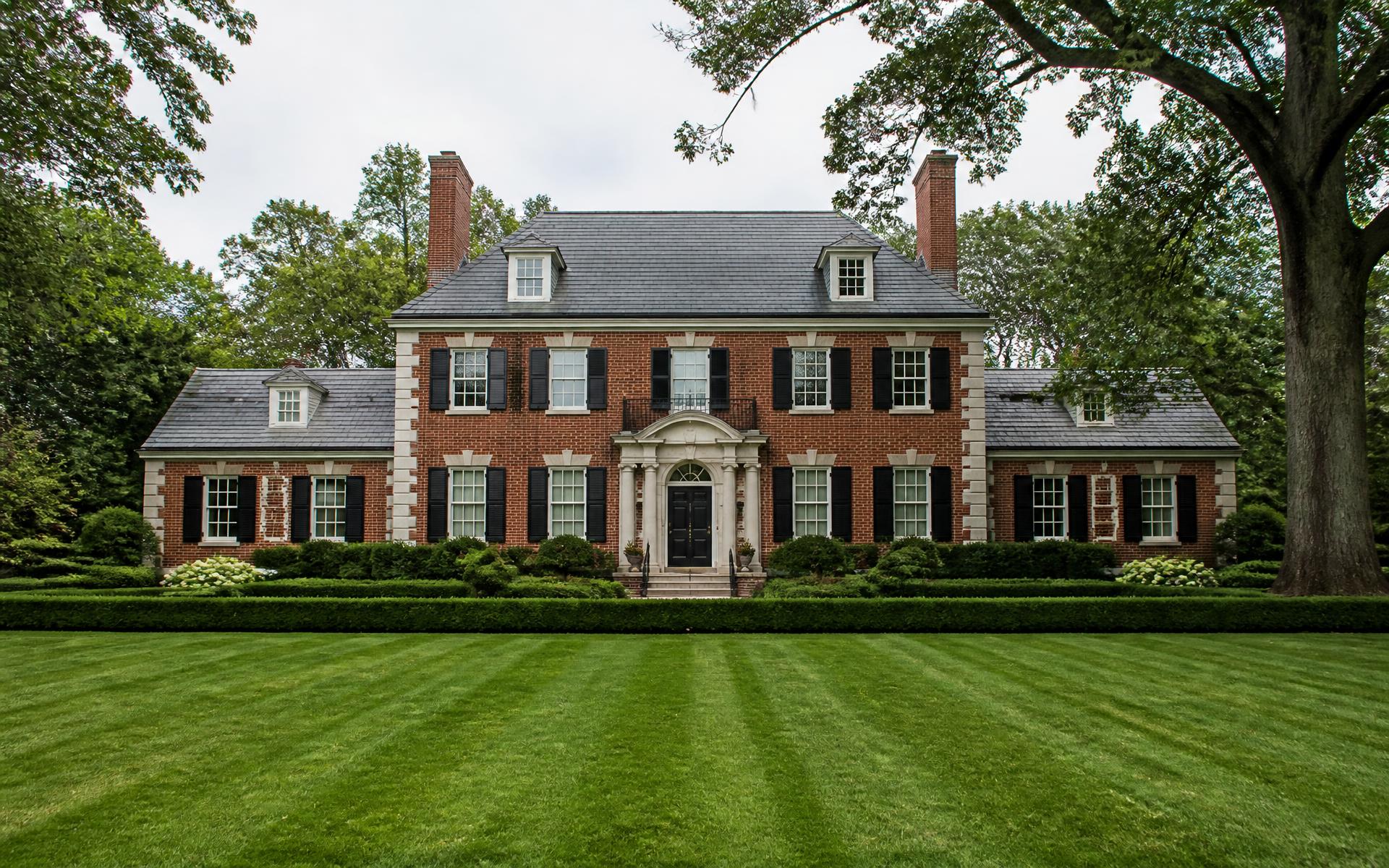 Symmetrical red brick Georgian Revival estate behind a clipped hedge in Myers Park