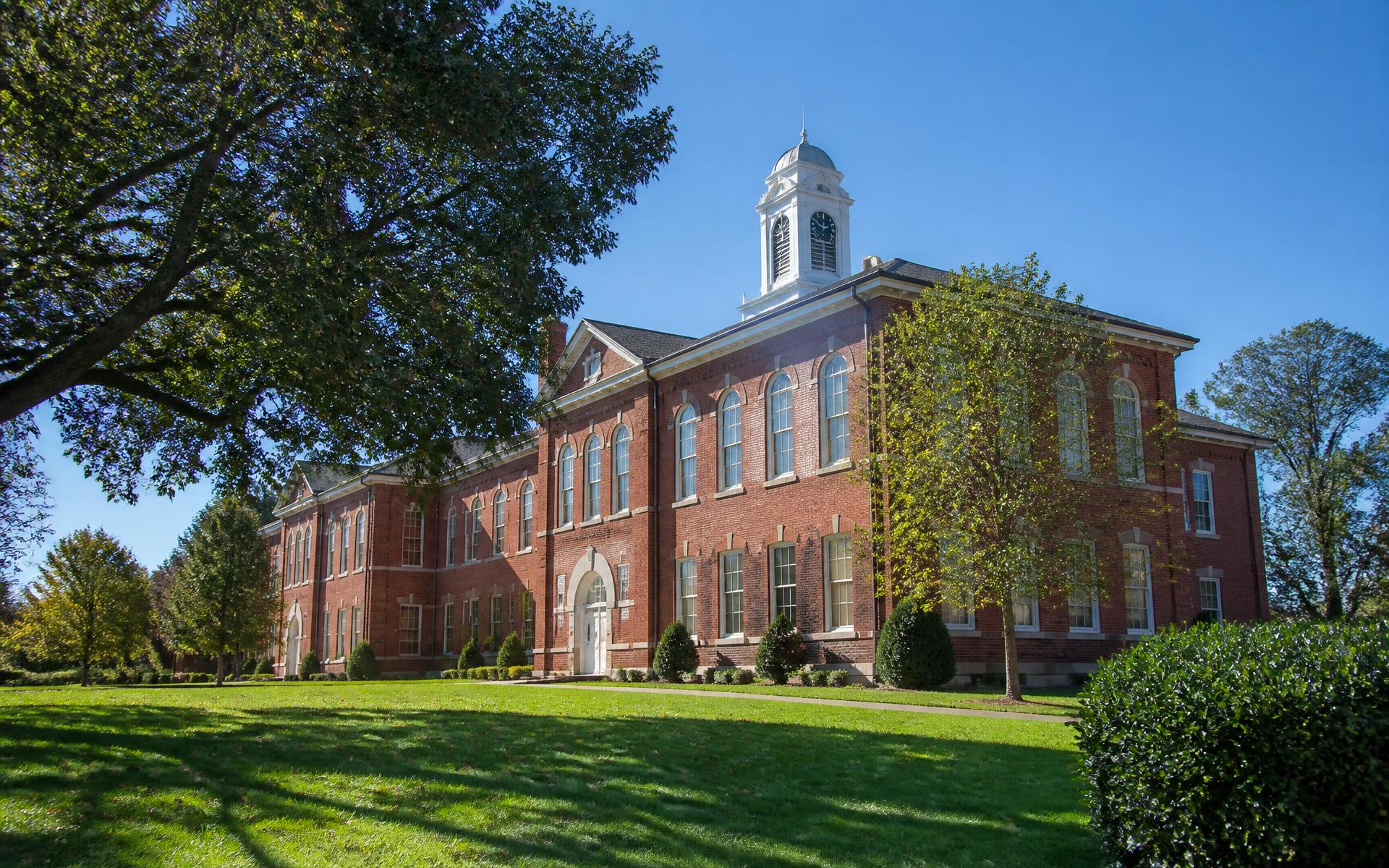 Historic brick school building with a white clock cupola near Myers Park, Charlotte
